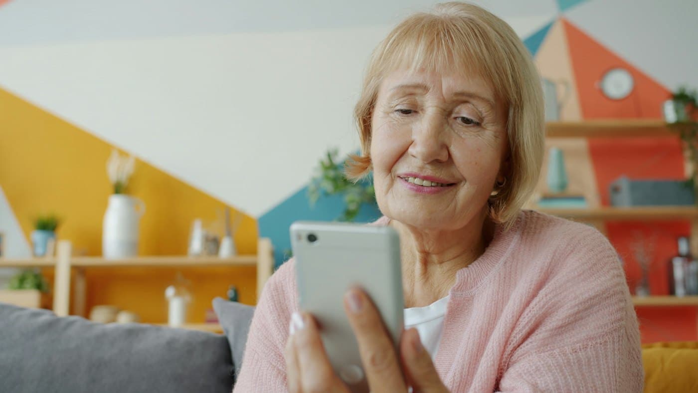 Ældre kvinde der smiler til sin mobil